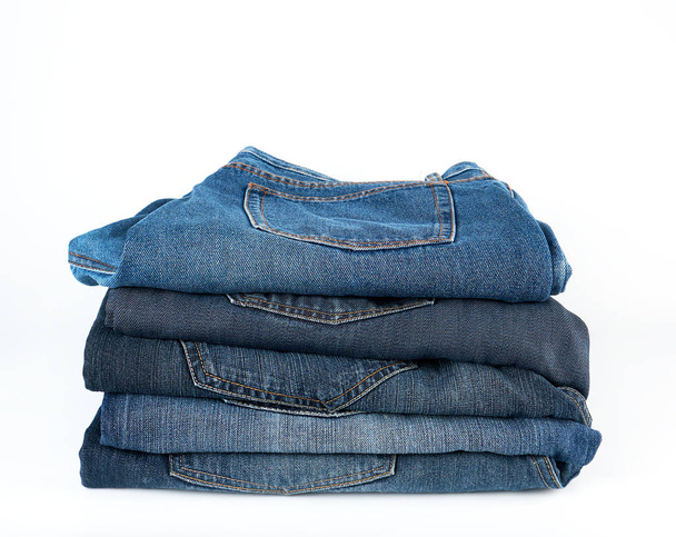 стопка сложенных синих джинсов на белом фоне - Фото, изображение