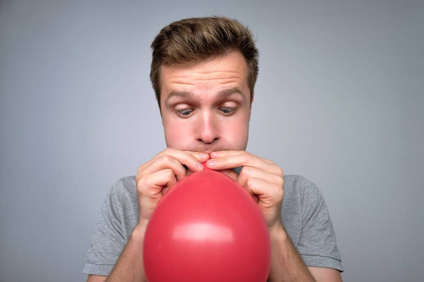 Jovem europeu explode um balão vermelho
 - Foto, Imagem