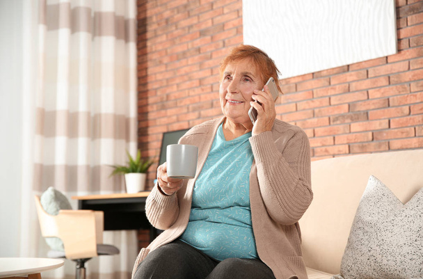 Elderly woman talking on phone in living room - Fotoğraf, Görsel