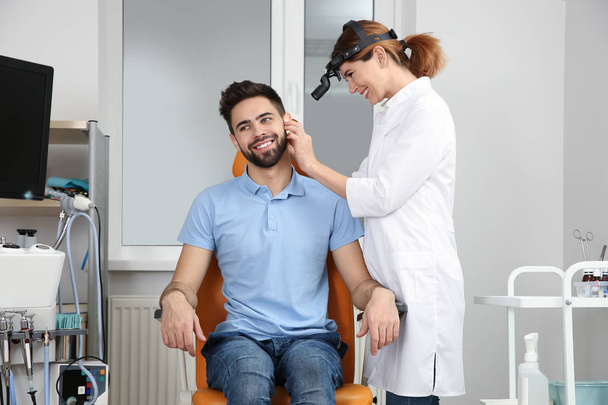 Professional otolaryngologist examining man in clinic. Hearing disorder - Foto, imagen