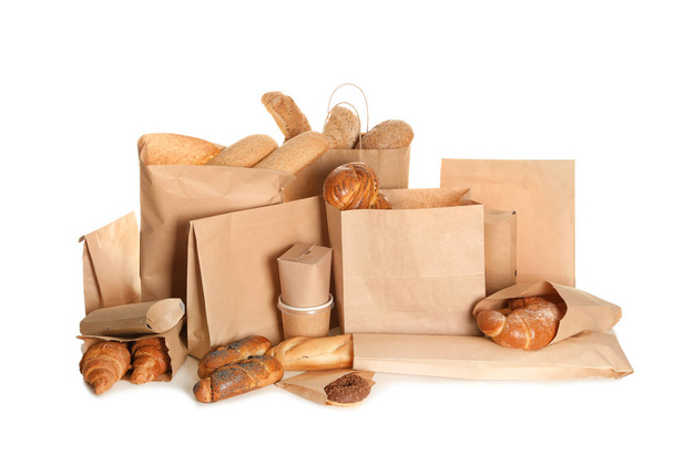 Different fresh bakery products in paper bags on white background - Foto, Bild