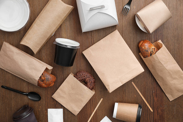 Flat lay composition with paper bags and different takeaway items on wooden background. Space for design - Foto, imagen