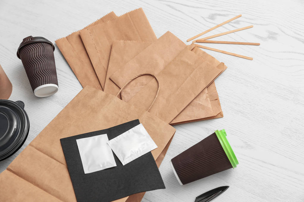 Paper bags and different takeaway items on wooden background. Space for design - Фото, изображение