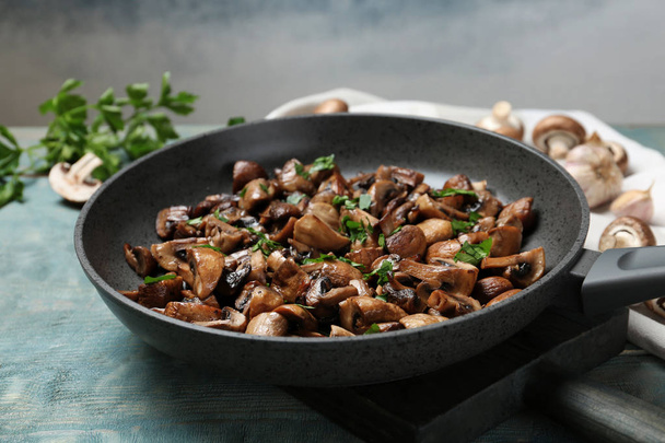 Frying pan with mushrooms on wooden table, closeup - Fotó, kép