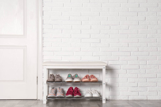 Shoe storage bench with different sneakers near brick wall, space for text - Foto, immagini