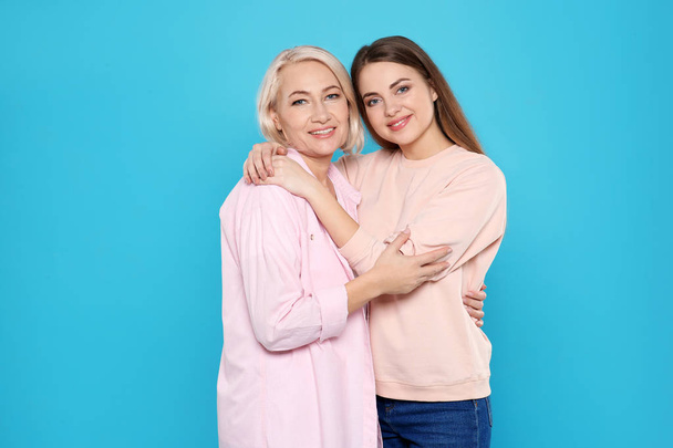 Portrait of mature woman and her daughter on color background - Foto, afbeelding