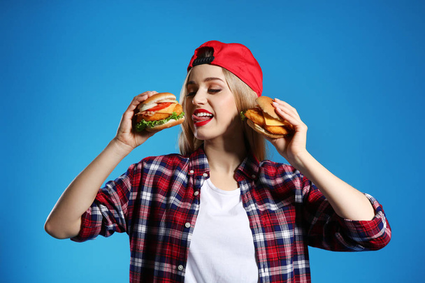Pretty woman with tasty burgers on color background - Фото, зображення