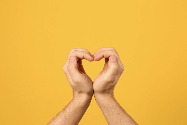 Человек, создающий сердце руками на цветном фоне, крупным планом
 - Фото, изображение