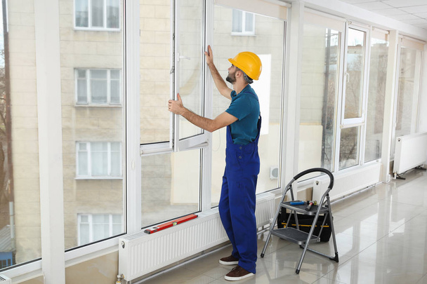 Construction worker installing plastic window in house - Fotoğraf, Görsel