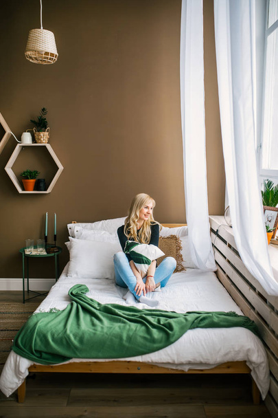 Blonde woman dreams in bed near light window at home - Photo, Image