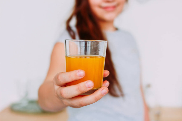 The girl holding glass of orange juice in hand, selective focus - Фото, изображение