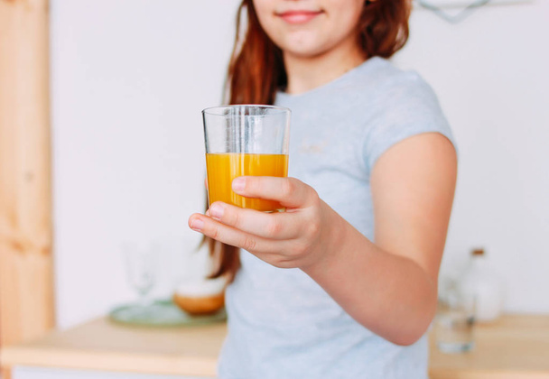The girl holding glass of orange juice in hand, selective focus - Foto, Imagen