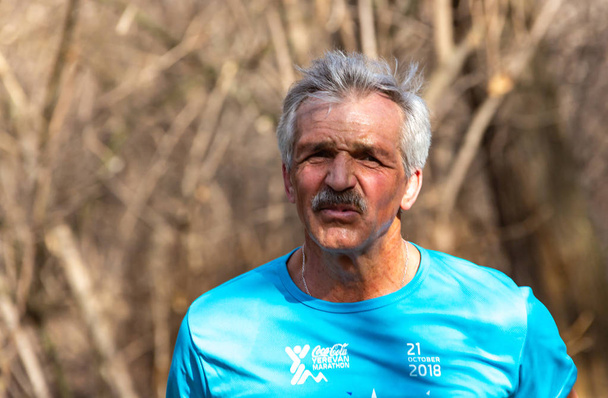 ALMATY, KAZAKHSTAN - 16 de marzo de 2019: retrato de un anciano desconocido que corre por el bosque durante la maratón de primavera en la ciudad de Almaty, en el bosque que lleva el nombre de Baum el 16 de marzo.
 - Foto, imagen