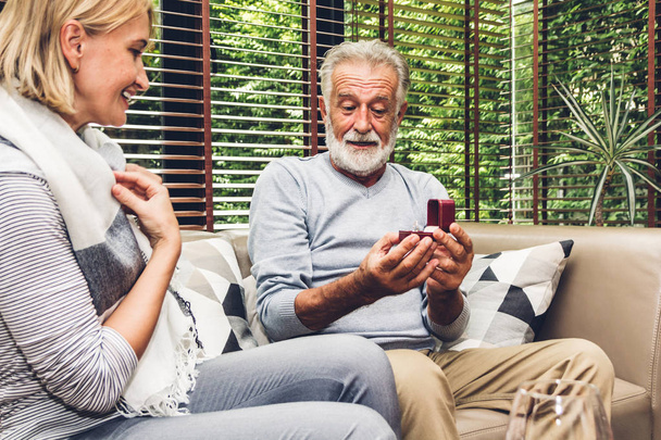 Hombre mayor dando anillo a la esposa y hablando juntos sentado en s
 - Foto, imagen