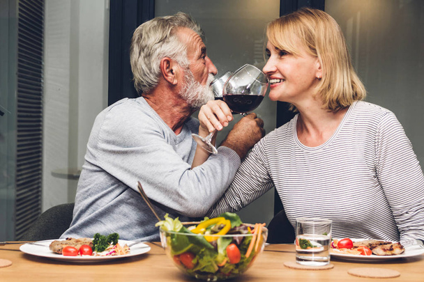 長老の老夫婦の笑顔幸せな夕食を食べたり飲んだり勝つ - 写真・画像