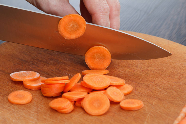 Szakács kezek sárgarépa vágódeszka, fából készült táblán - Fotó, kép