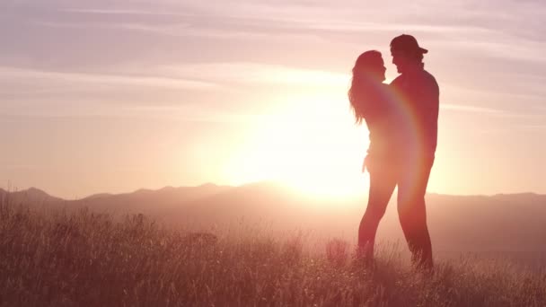 Młoda zakochana para odpoczywa w górach o pięknym zachodzie słońca - Materiał filmowy, wideo