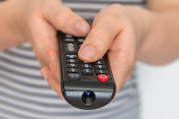 Remote control in female hands pointing to TV - Foto, Imagen