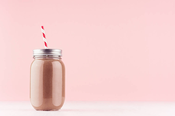 Sweet chocolate milkshake in old fashioned jars with  straw, silver cap on light pastel pink background. - 写真・画像