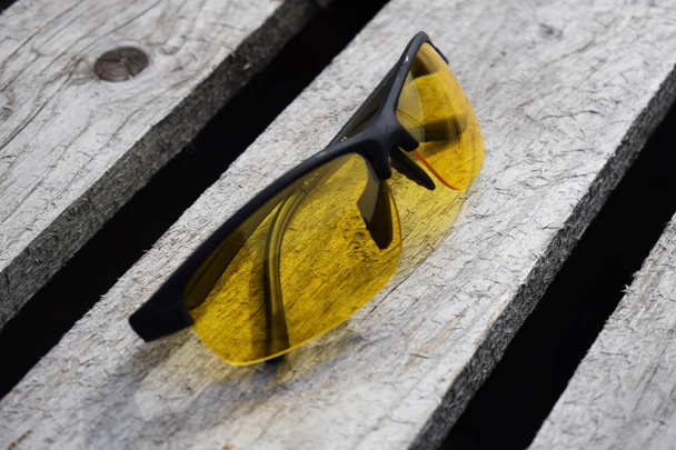 Gafas amarillas de seguridad sobre fondo de madera. Las gafas mienten
. - Foto, imagen