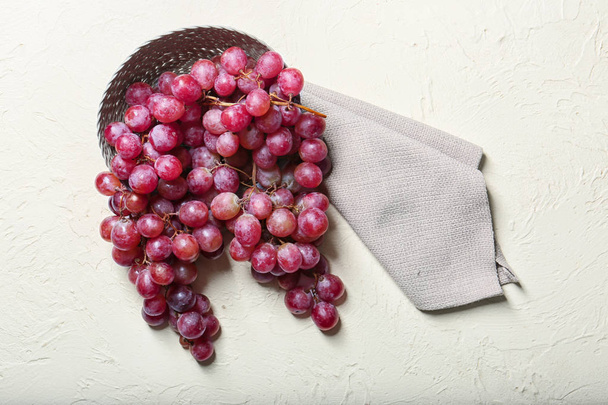 Bol en osier avec raisins rouges sur fond blanc texturé
 - Photo, image
