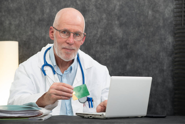 senior bearded doctor with health insurance card - Foto, imagen