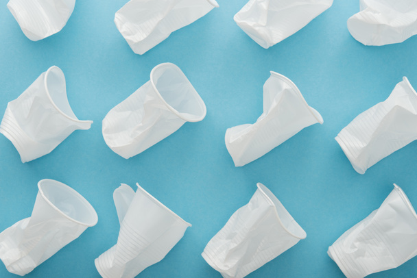 top view of white and crumpled plastic cups on blue background  - Foto, Imagen