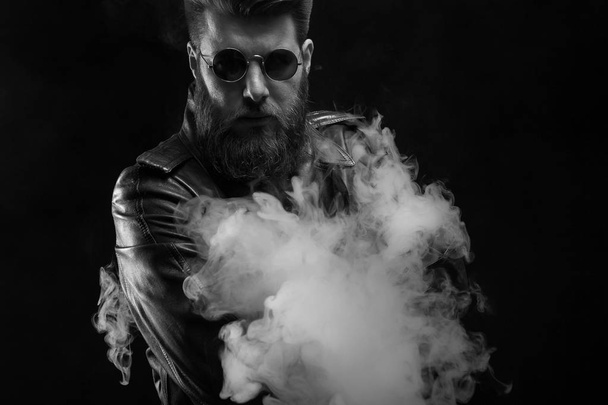 Ritratto in bianco e nero di uomo serio che indossa una giacca di pelle in studio photoshoot su sfondo nero
 - Foto, immagini