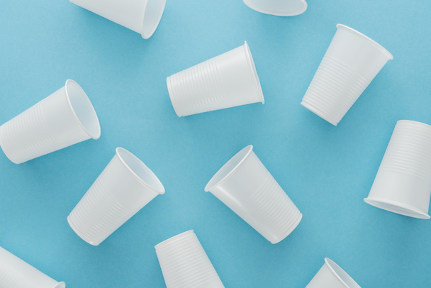 top view of white and plastic cups on blue background  - Fotoğraf, Görsel