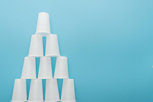 flat lay with white plastic cups on blue background with copy space  - Zdjęcie, obraz