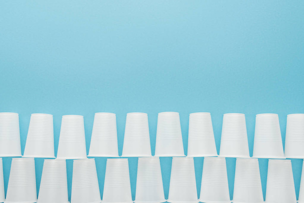 flat lay with white plastic cups isolated on blue with copy space  - Fotó, kép