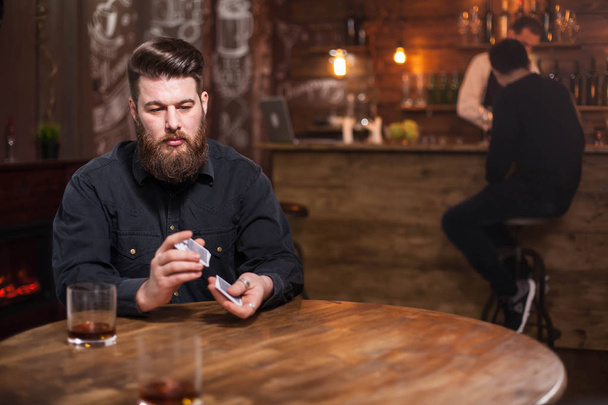 Guapo barbudo perdido en sus pensamientos junto a un vaso de whisky
 - Foto, Imagen
