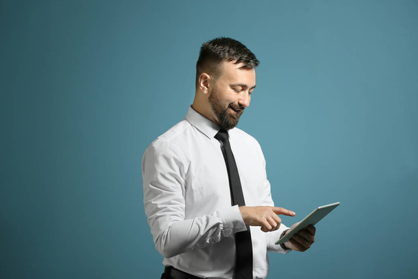 Портрет красивого бизнесмена с планшетным компьютером на цветном фоне
 - Фото, изображение