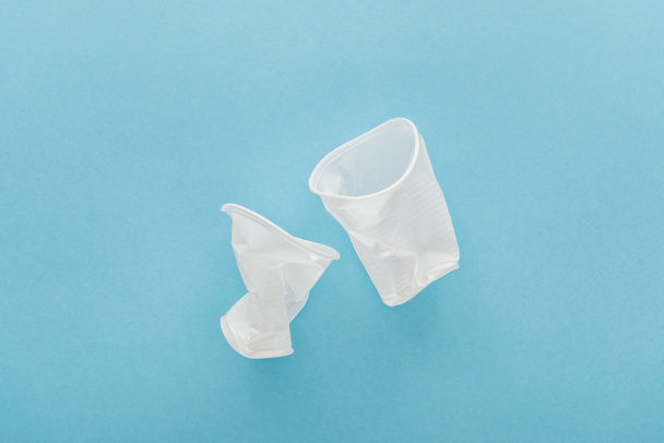 top view of white plastic cups on blue background with copy space  - Fotó, kép