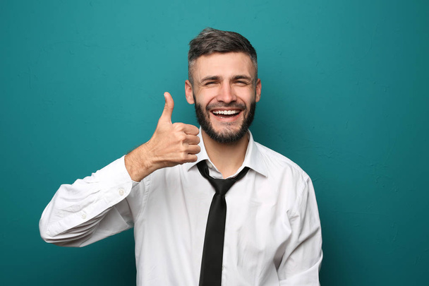 glücklicher Geschäftsmann zeigt Daumen-hoch-Geste auf farbigem Hintergrund - Foto, Bild