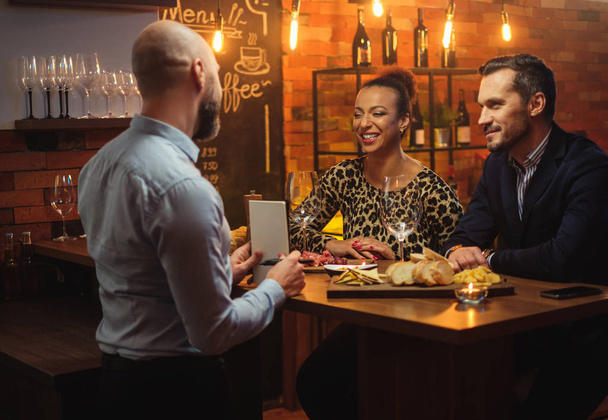 Пара беседующих с барменом за барной стойкой в кафе
 - Фото, изображение