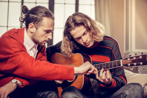 Bearded guitar tutor feeling busy teaching his talented student - Photo, image