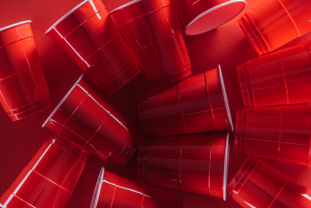 vista superior de copos de plástico brilhantes e coloridos no fundo vermelho
  - Foto, Imagem