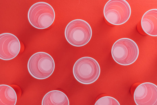вид зверху яскравих і барвистих пластикових чашок на червоному тлі
  - Фото, зображення