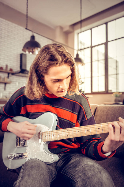 Student with bob cut getting satisfaction playing the guitar - Fotografie, Obrázek