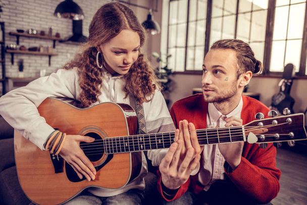 Older brother helping his cute teenage sister playing the guitar - Fotografie, Obrázek