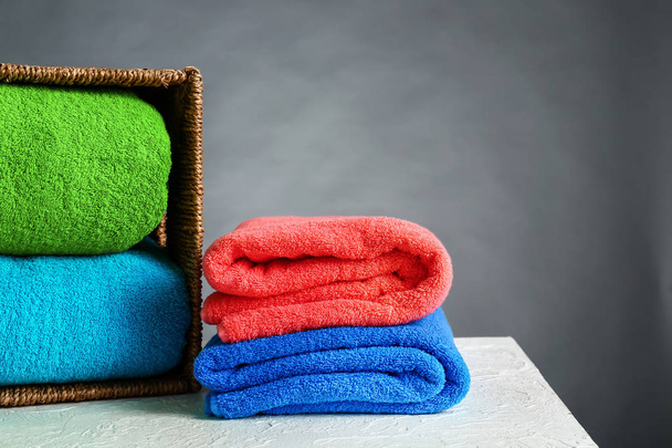 Плетеная корзина с цветными полотенцами на столе
 - Фото, изображение