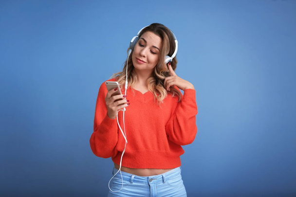 Porträt einer schönen jungen Frau, die Musik auf farbigem Hintergrund hört - Foto, Bild