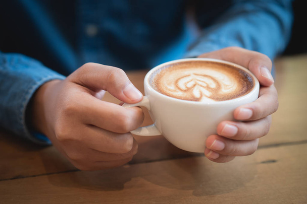 Man hands holding a cup of coffee on wooden table - Foto, Bild