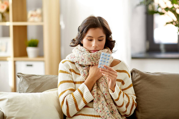 sick woman in scarf with medicine pills at home - Foto, Bild