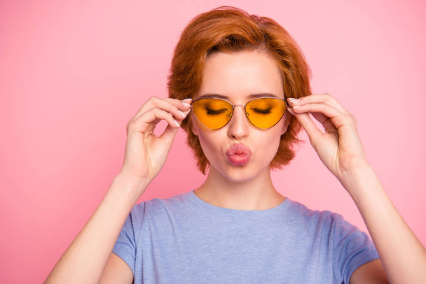 Close-up portrait of her she nice cute charming attractive lovely winsome sweet girl wearing casual blue t-shirt yellow glasses sending you kiss isolated over pink pastel background - Фото, изображение