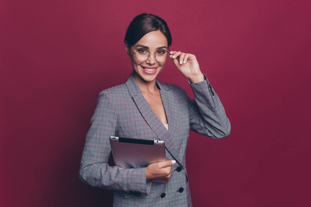 Portrait of her she nice cute attractive lovely sweet cheerful lady ceo boss chief in gray checkered blazer holding in hands ebook touching glasses isolated over maroon burgundy marsala background - Foto, imagen