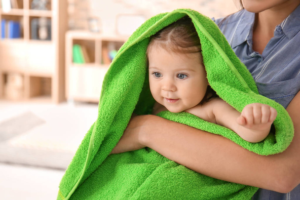 Young mother with cute little baby wrapped in soft towel at home - Photo, Image