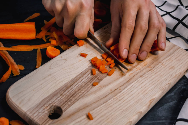 Porkkanan leikkaaminen puulaudalla aterian valmistusta varten
 - Valokuva, kuva