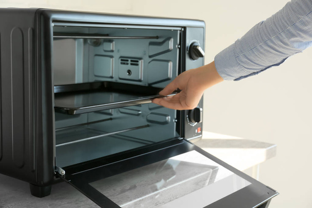 Vrouw bakplaat ingebruikneming elektrische oven - Foto, afbeelding